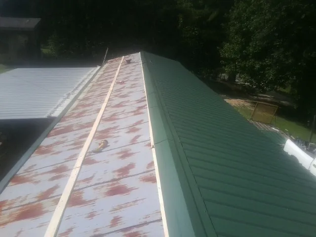 Old rusted panels beside newly installed green metal roofing — Wind Damage Roof Repair by Roofing Brothers in Hurley