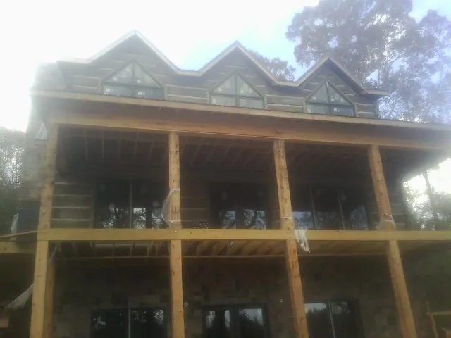 Dormers and porch framing on a large log home under construction — Roof Coating work by our crew in Hurley