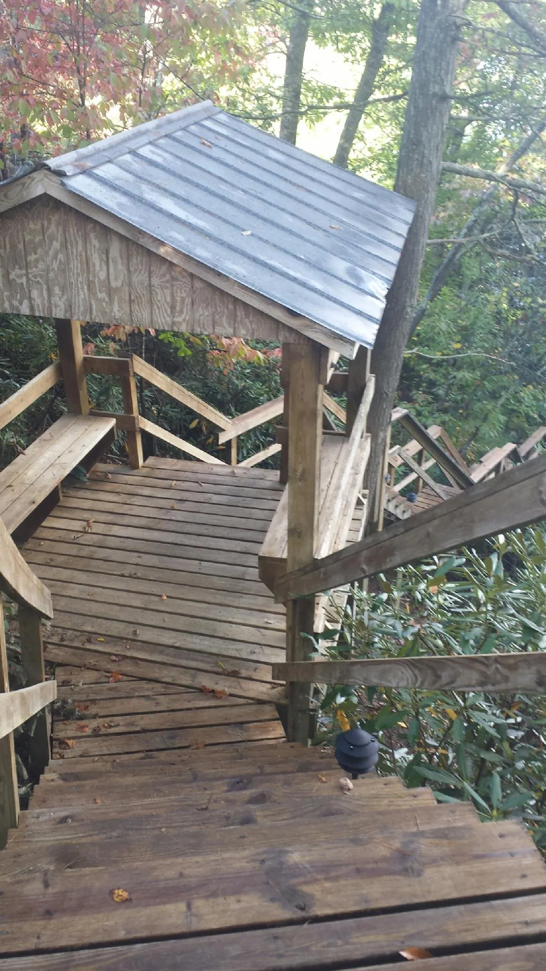 Metal roofed shelter over wooden steps on a wooded walkway — Skylight Repair & Installation work by our crew in Hurley